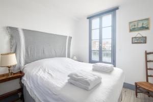 een slaapkamer met een wit bed en handdoeken bij Appartement L'Îlot au centre du port de Saint Martin in Saint-Martin-de-Ré