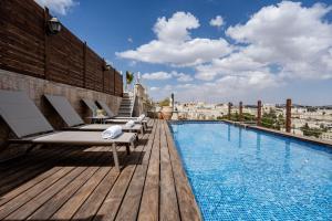 a swimming pool with chaise lounges on a building at King David Penthouse with private pool in Jerusalem
