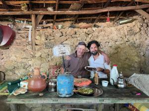 dwóch mężczyzn stojących przed stołem z jedzeniem w obiekcie Le Sommet Naturel w mieście Szafszawan