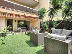 a backyard with wicker furniture and a yard with grass at Rabiac - Charming 1 bedroom with private garden in Antibes