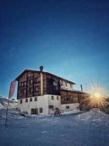 a building in the snow with the sun in the background at Chalet Sepp in Belalp
