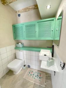 a bathroom with a toilet and a sink and green cabinets at The Cliffs - Casa Valdeflores in Viveiro