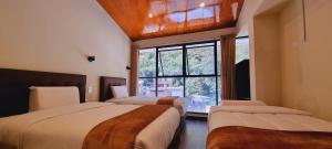 una camera da letto con due letti e una finestra di Hotel Raices Machupicchu a Machu Picchu