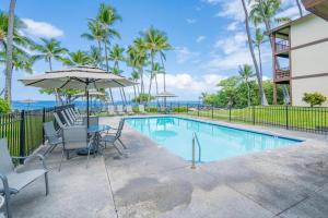 uma piscina com cadeiras e um guarda-sol em Kona Isle C38 em Kailua-Kona