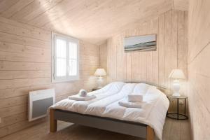 a bedroom with a bed with white sheets and a window at Petite maison de village Eloise proche de la plage in Sainte-Marie-de-Ré