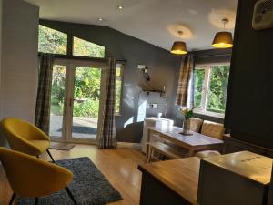 a living room with a table and a yellow chair at The Reading whole chalet with lake and two acre gardens in Reading