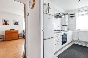 Biała kuchnia z białymi szafkami i oknem w obiekcie Flat 13 w Londynie