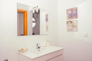 uma casa de banho branca com um lavatório e um espelho em Namastê House I em Relógio do Poiso