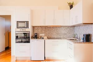 a white kitchen with white cabinets and appliances at Namastê House I in Relógio do Poiso