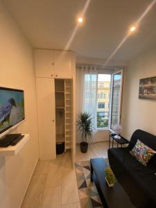 a living room with a black couch and a large window at Studio sur avenue jean médecin à Nice in Nice