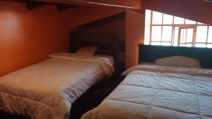 a bedroom with two beds and a window at Hosteria Loma Larga Cayambe in Cayambe