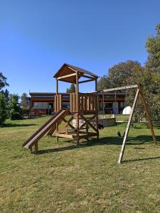 um parque infantil de madeira com um escorrega num campo em El Montenegrino em Tandil