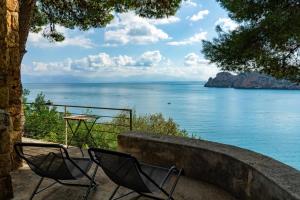 two chairs sitting next to a table and the ocean at Scopello Villa sul Mare in Scopello