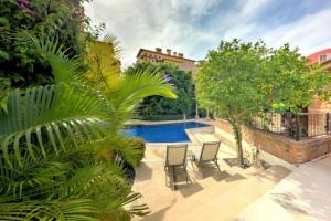 a backyard with a swimming pool and chairs and trees at Beachside Bliss Studio, Walk to the Marina and Beach in Cabo San Lucas