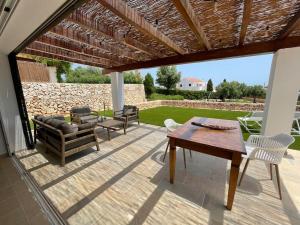un patio con mesa, sillas y pared de piedra. en Villa Can Simo Menorca, en Punta Prima