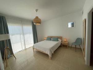 um quarto com uma cama branca e uma cadeira azul em Villa Can Simo Menorca em Punta Prima
