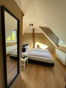 Schlafzimmer im Dachgeschoss mit einem Bett und einem Spiegel in der Unterkunft AUERSTEIN-Hotels auerstein & auerstein-mono in Heidelberg