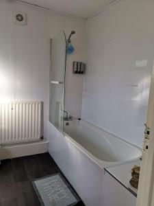 baño blanco con bañera y ducha acristalada en The Superhost - 4 BR House en Sunderland