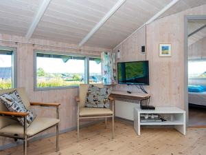 Habitación con 2 sillas, escritorio y TV. en 6 person holiday home in R nde, en Rønde