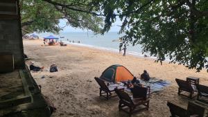 um grupo de pessoas sentadas numa praia com uma tenda em Kampong Style Homestay Pengkalan Balak - Sea View em Pengkalan Balak