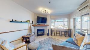 a living room with a couch and a fireplace at 1BR plus Den Village Condo with Mountain Views and Hot Tub by Harmony Whistler in Whistler