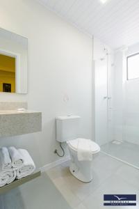 uma casa de banho branca com um WC e um chuveiro em Gaivotas Praia Hotel em Florianópolis