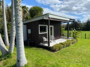 a small cabin with a porch and palm trees at The Perfect Dogbox in a tropical country setting! in Omaha