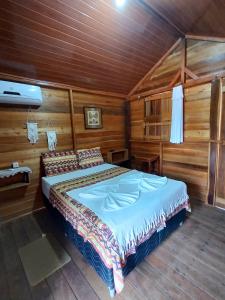 um quarto com uma cama num quarto de madeira em Pousada AldeiA Cotijuba em Belém