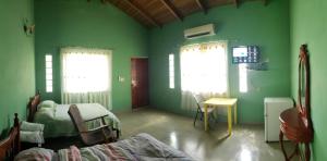 um quarto verde com uma cama, uma mesa e janelas em cabañas playa guanico em Tonosí