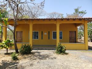 una casa gialla con un albero di fronte di cabañas playa guanico a Tonosí