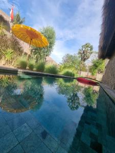 a pool with an umbrella and a swimming pool at Flow Gili Air in Gili Islands