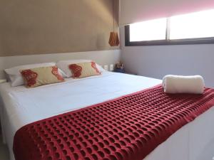 a large white bed with a red blanket on it at Elegante quarto e sala Sky Concept 418 Novissímo in Maceió