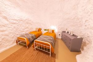two twin beds in a room with a wall at Daybreak Dugout Luxury Underground House in White Cliffs
