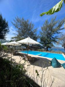 een zwembad met 2 stoelen en een parasol bij 7SEAS Cottages in Gili Air