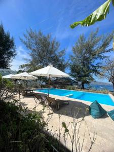 a swimming pool with two chairs and an umbrella at 7SEAS Cottages in Gili Air