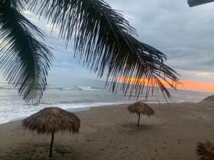 翡翠海濱的住宿－Mar De Estrellas - Hotel，海滩上的两把草伞和大海