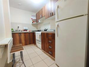 una cucina con frigorifero bianco e armadietti in legno di Acogedora Habitación en Miraflores a Lima