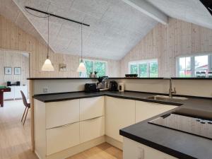 uma cozinha com armários brancos e bancadas pretas em Holiday home Dannemare XXXV em Dannemare