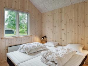 Duas camas num quarto com paredes de madeira e uma janela em Holiday home Dannemare XXXV em Dannemare