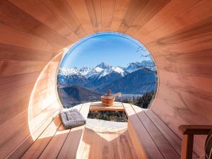 a round window in a wooden room with a table and a vase at CHALET LES CERISES Jacuzzi, Sauna, Hammam, Cinéma in Cordon