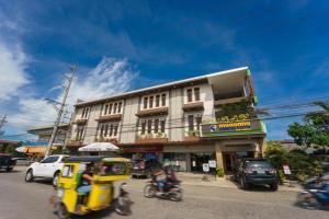 ulica z samochodami i ludzie na motocyklach i budynek w obiekcie Madonna Hometel and Suites New Pandan w mieście Panabo