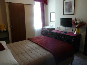 a bedroom with a bed and a television on a desk at Melbourne Guest House in Rhyl