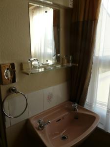 a bathroom with a sink and a mirror and a window at Melbourne Guest House in Rhyl