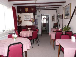 a dining room with pink tables and red chairs at Melbourne Guest House in Rhyl