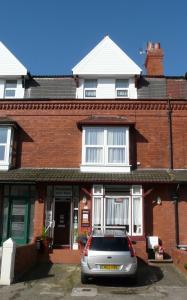 um carro prateado estacionado em frente a uma casa de tijolos em Melbourne Guest House em Rhyl