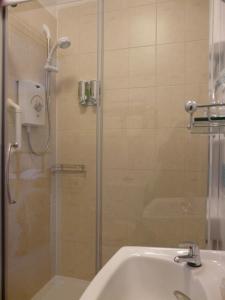 a shower with a glass door next to a sink at Melbourne Guest House in Rhyl