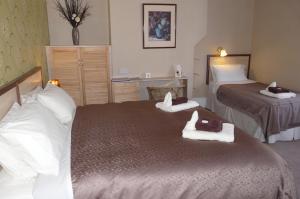 a hotel room with two beds with towels on them at Melbourne Guest House in Rhyl