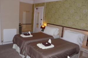 two beds in a hotel room with towels on them at Melbourne Guest House in Rhyl
