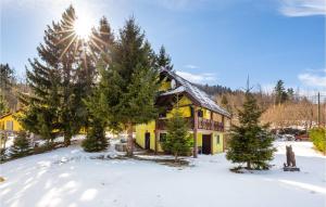 a yellow house in the snow with the sun shining at Cozy Home In Lokve With Jacuzzi in Lokve