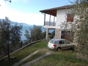 une voiture garée à côté d'une maison avec balcon dans l'établissement Villa Venturelli, à Tignale